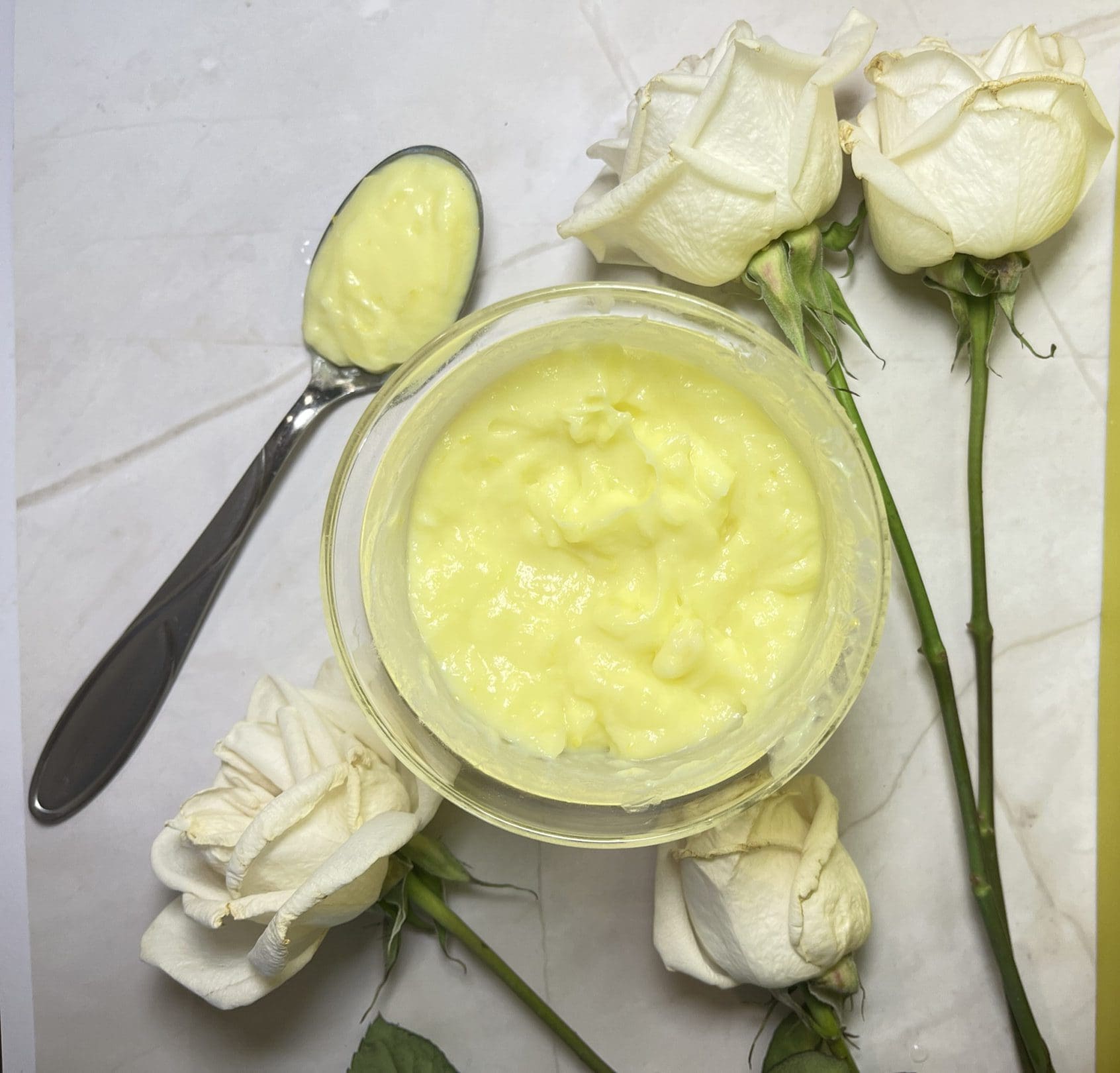 Yellow cream in bowl with white roses.