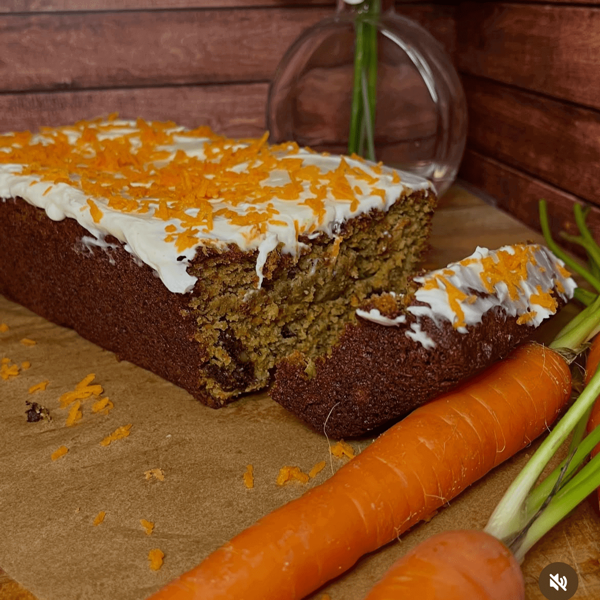 Carrot cake with frosting and fresh carrots.