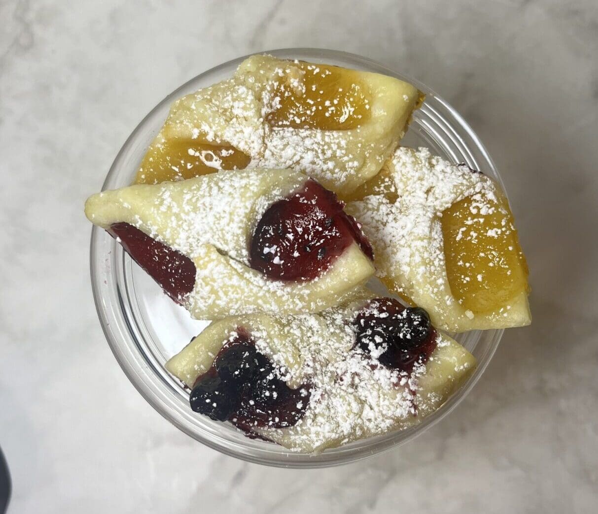 Pastries with fruit fillings and powdered sugar.