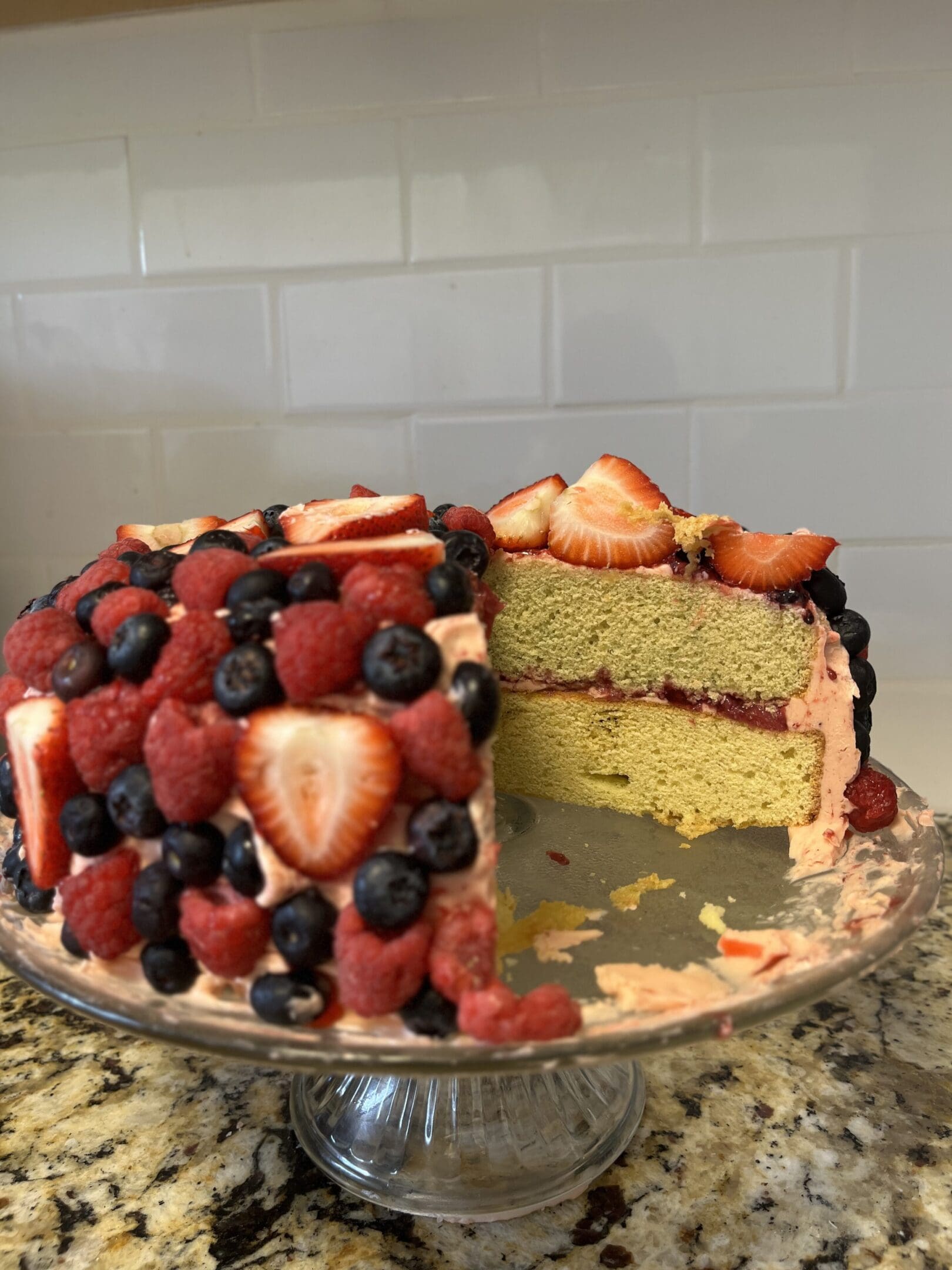 Cake with berries on a glass stand.