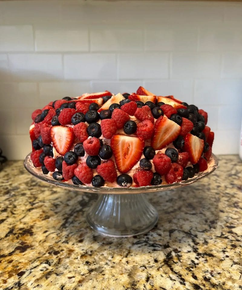 A vibrant fruit cake topped with strawberries, blueberries, and raspberries.