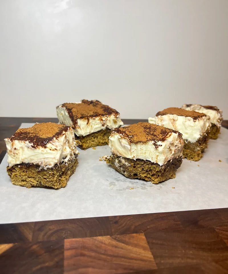 Close-up of layered dessert bars with cream and caramel topping.