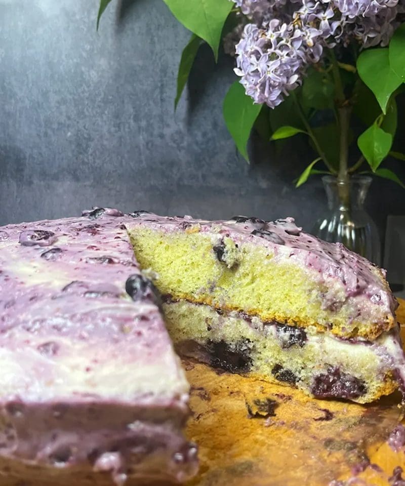A slice of blueberry cake with creamy purple frosting.
