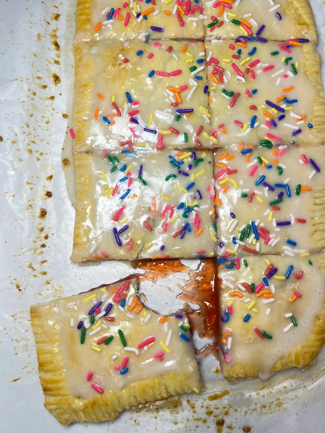 Frosted toaster pastry with colorful sprinkles, partially cut and served.