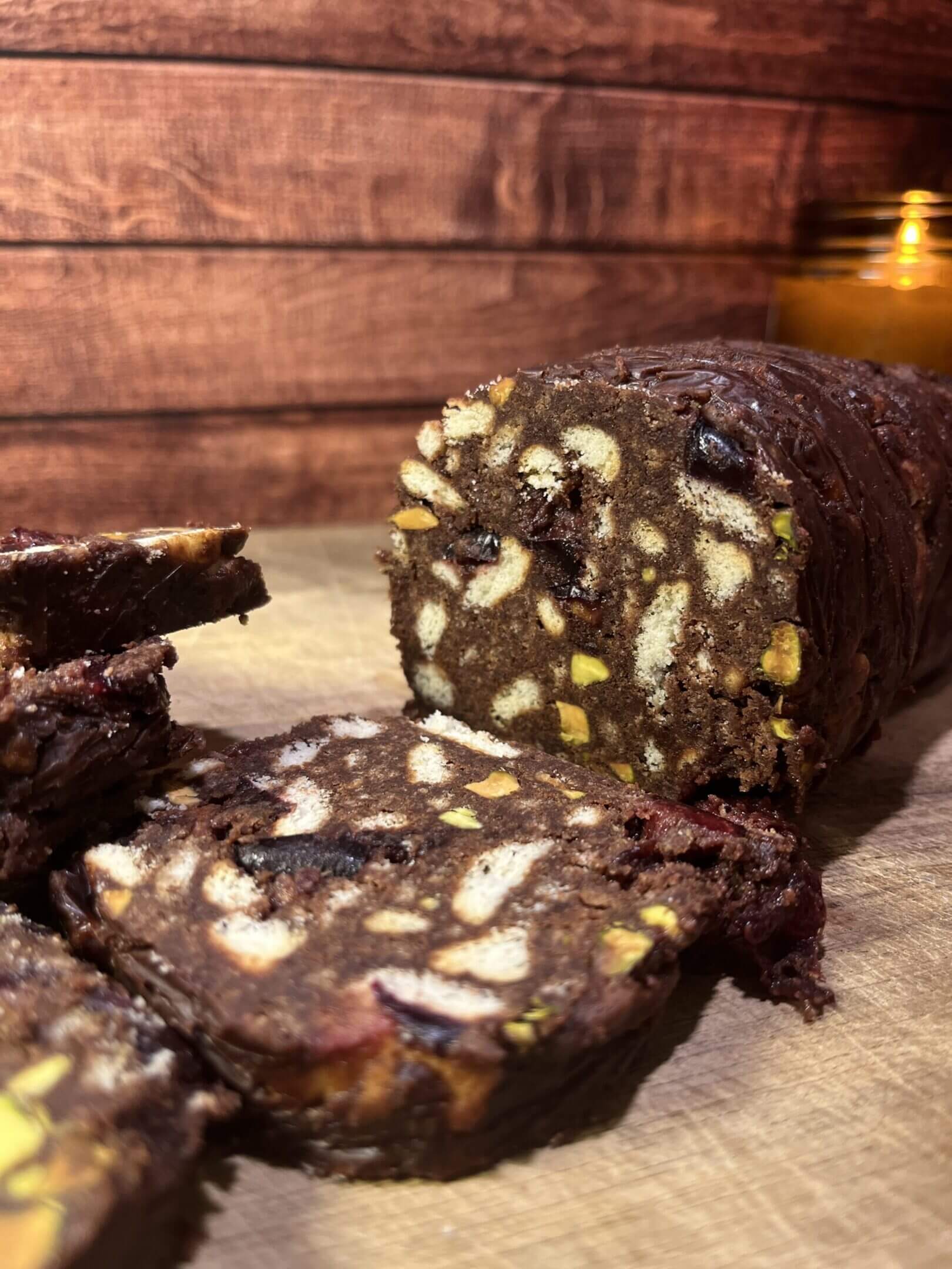 Chocolate salami with nuts on wooden surface.