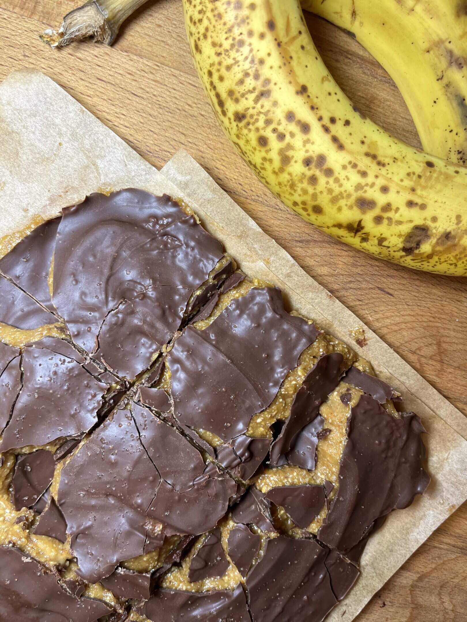 Chocolate-covered dessert with ripe bananas nearby.