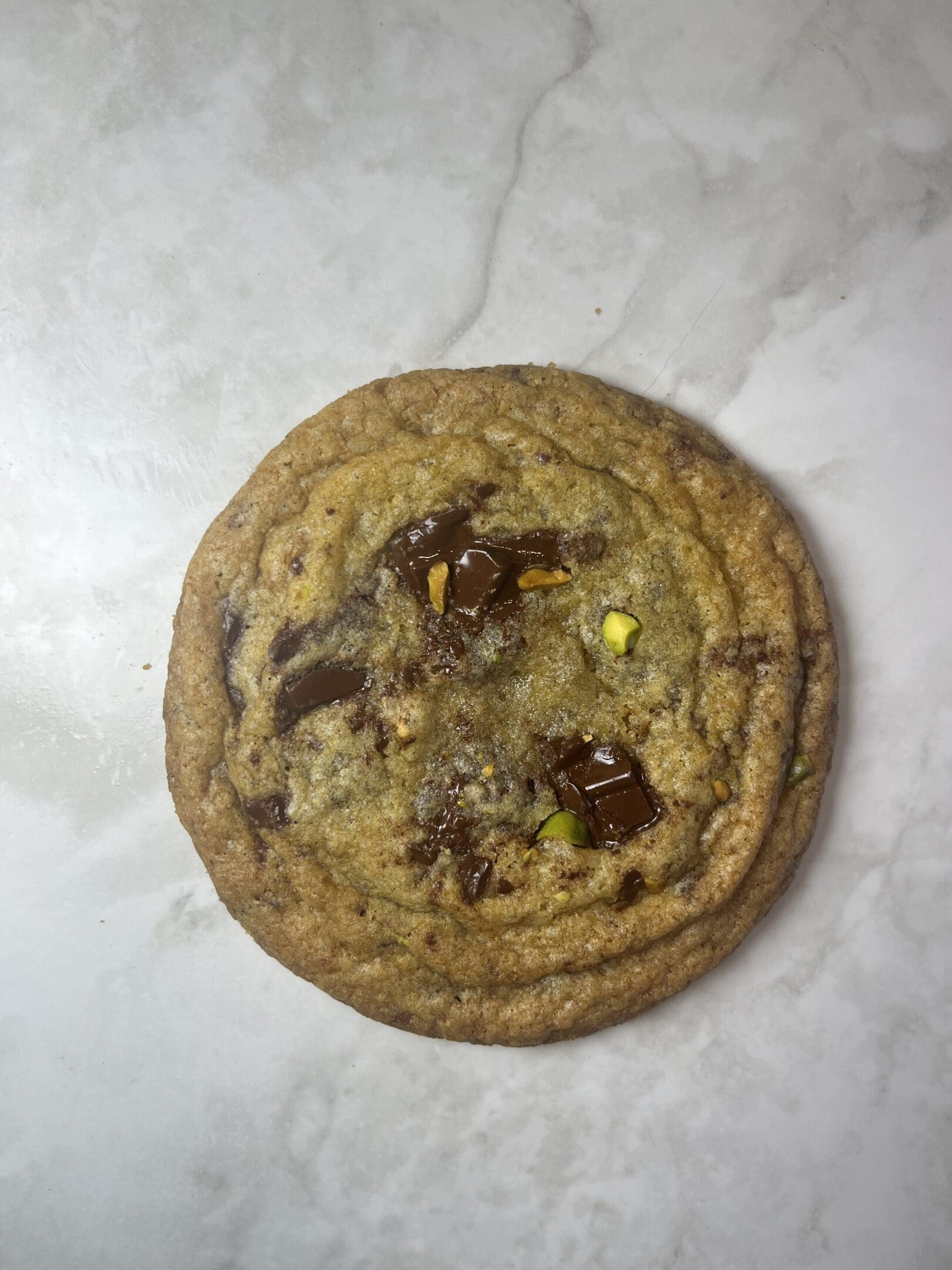 Chocolate chip cookie on marble surface.