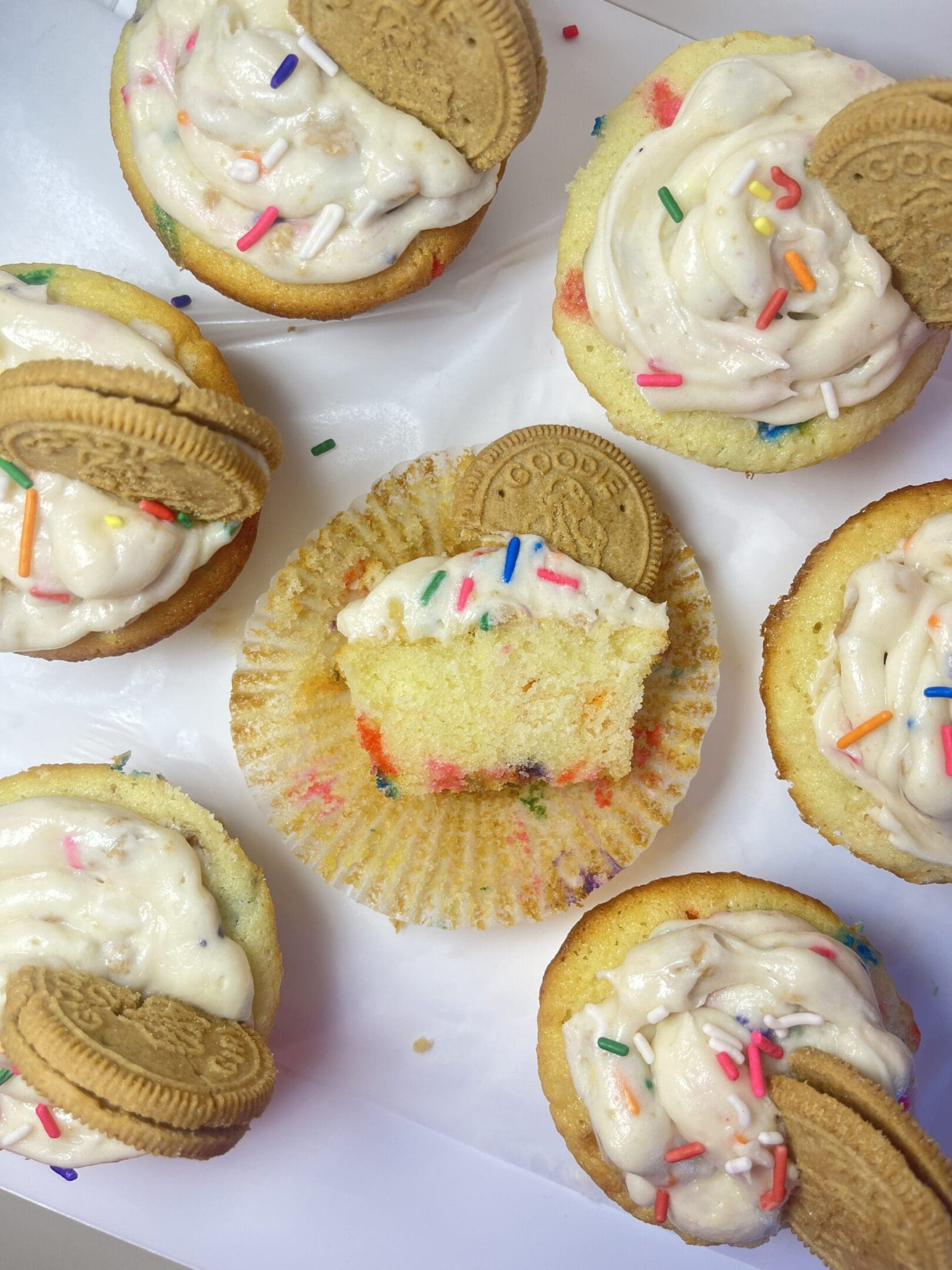 Cupcakes with frosting, sprinkles, and cookies.