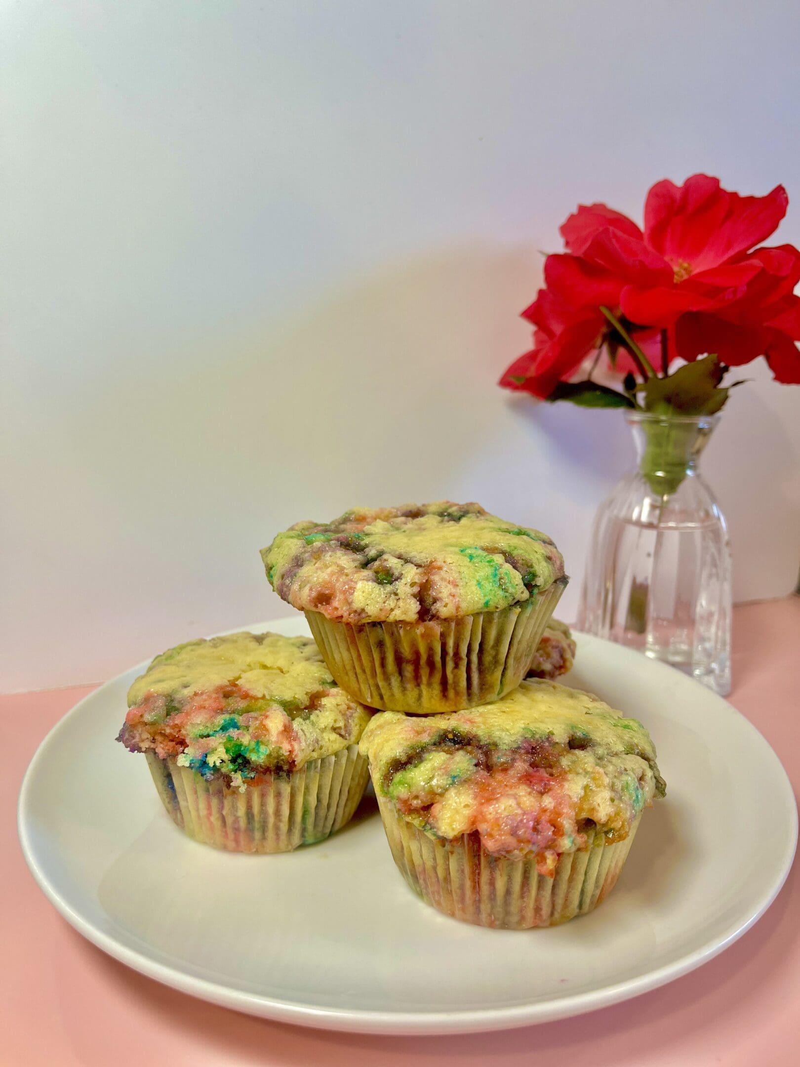 Colorful muffins on plate with red flowers.