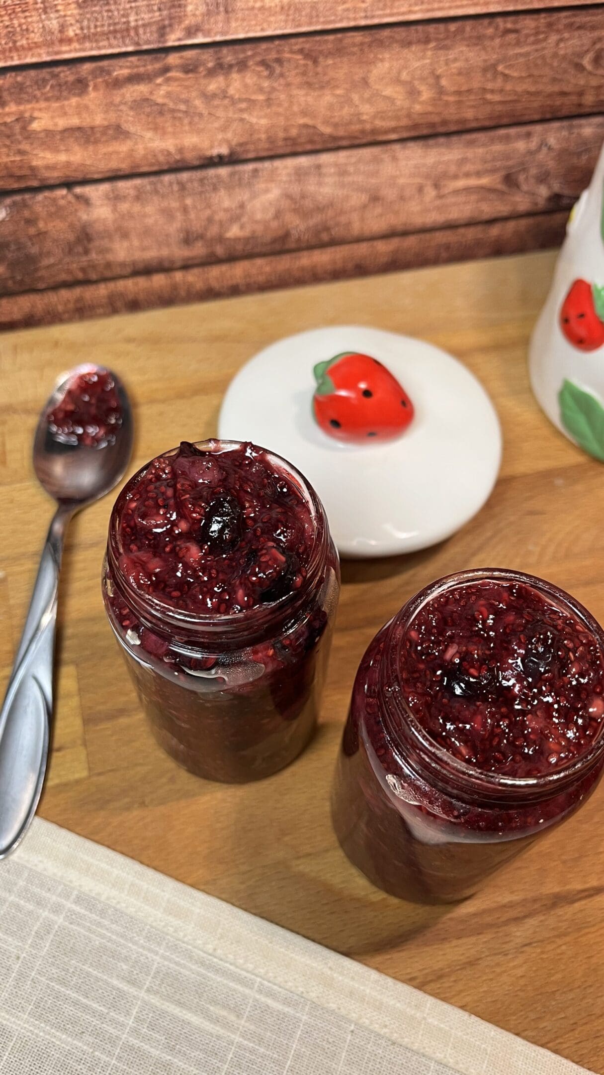 Jars of berry jam on wooden table.
