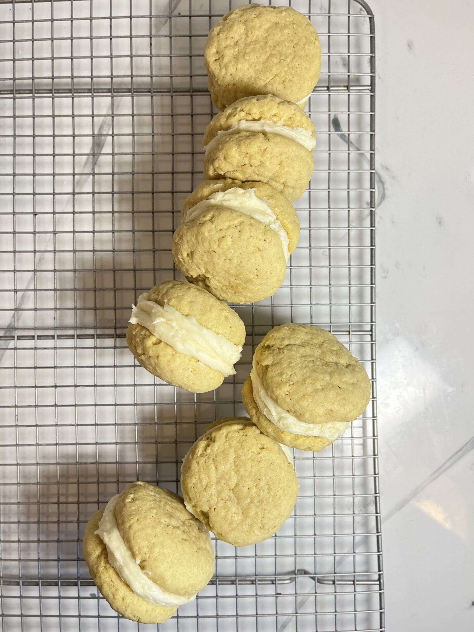 Cookies with cream filling on cooling rack.