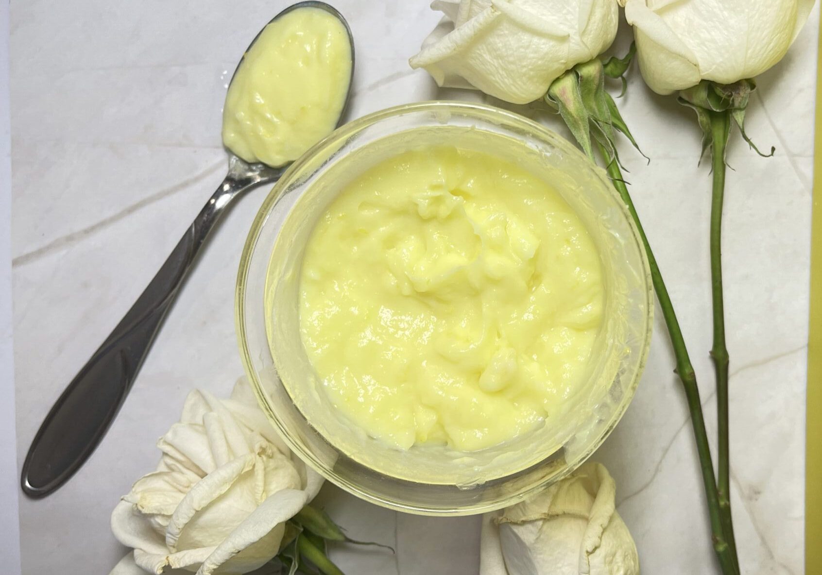 Yellow cream in bowl with white roses.
