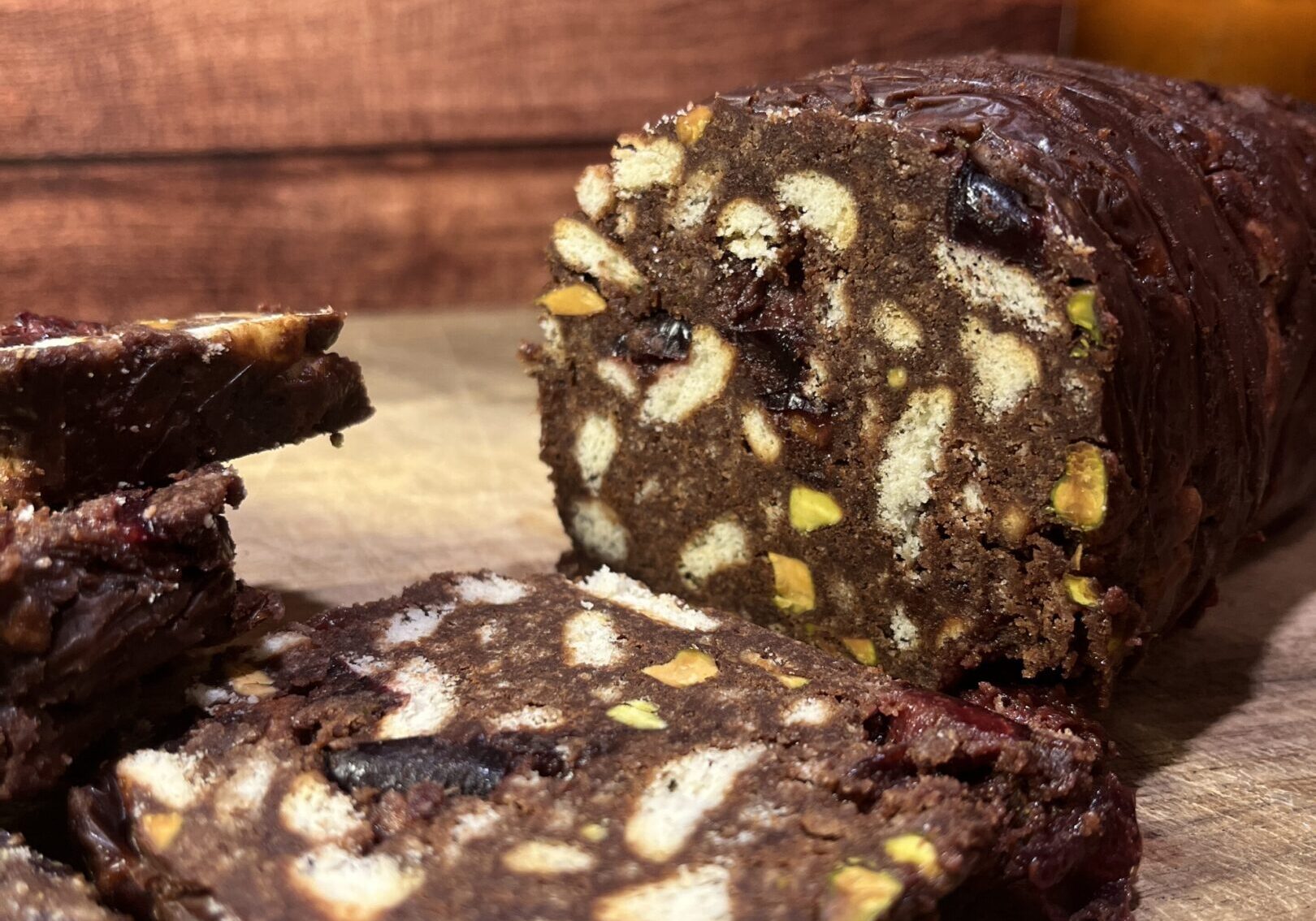 Chocolate salami with nuts on wooden surface.
