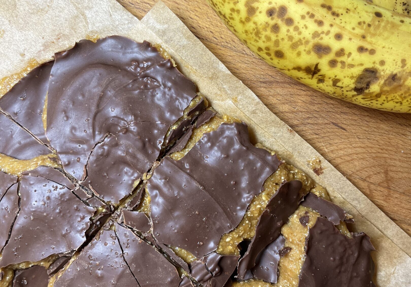 Chocolate-covered dessert with ripe bananas nearby.