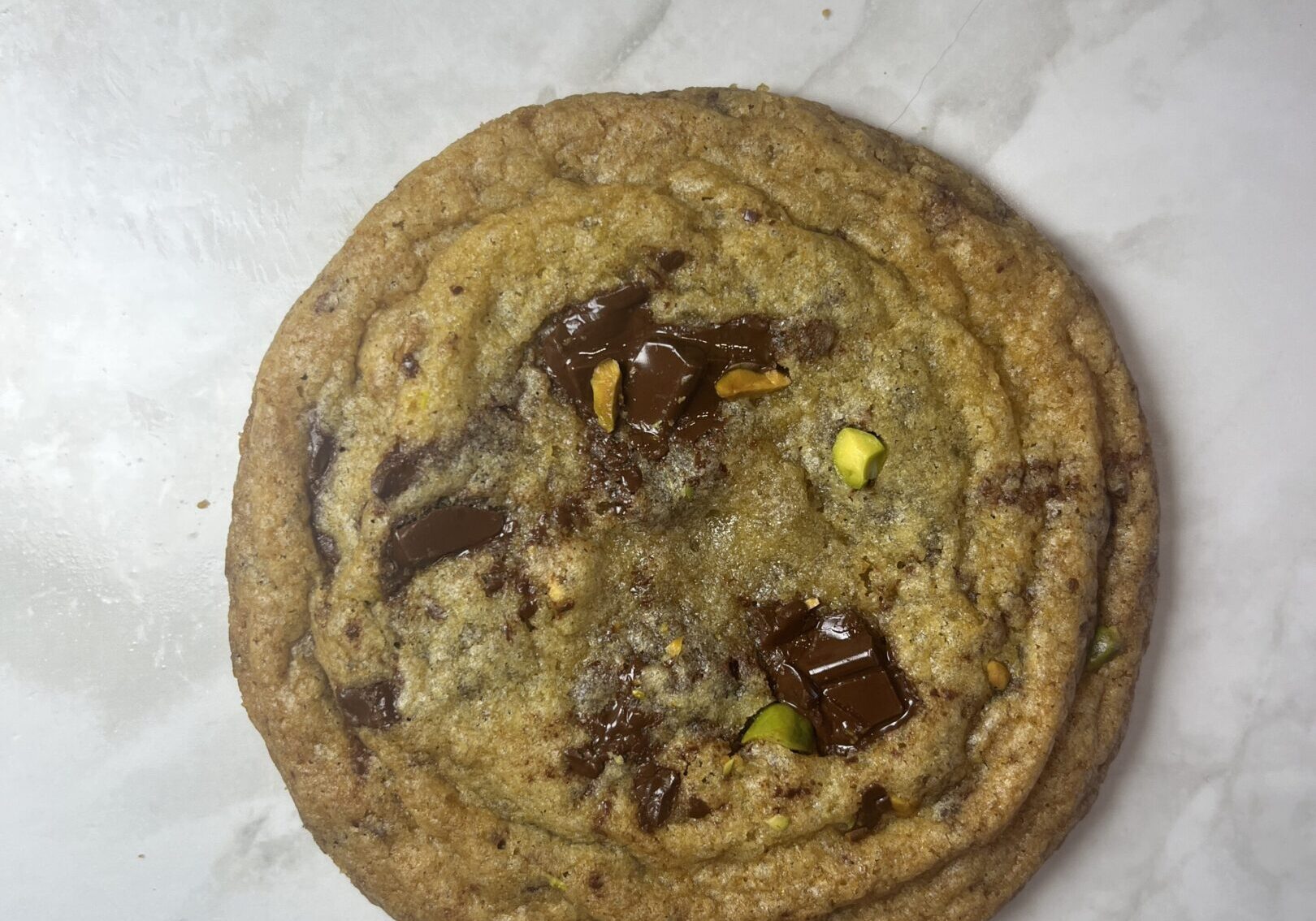 Chocolate chip cookie on marble surface.