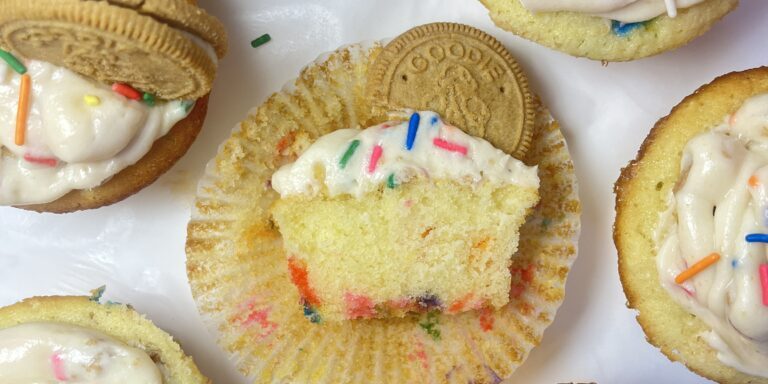 Cupcakes with frosting, sprinkles, and cookies.