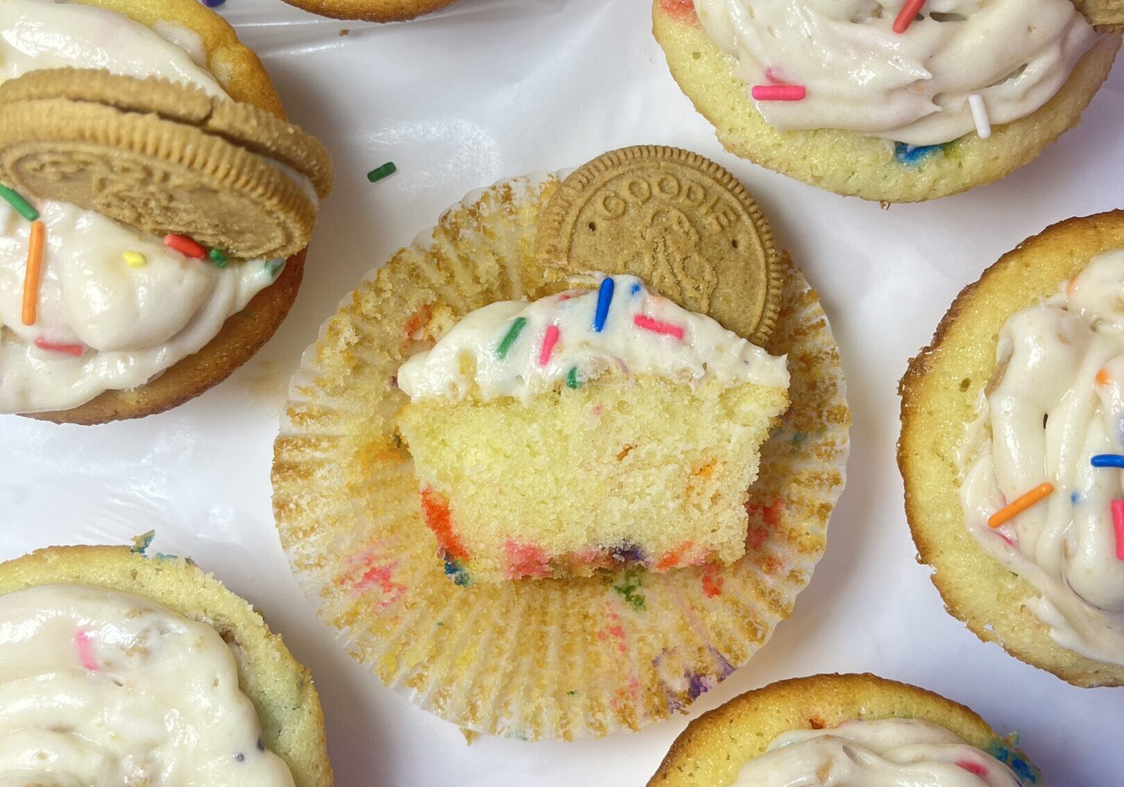 Cupcakes with frosting, sprinkles, and cookies.