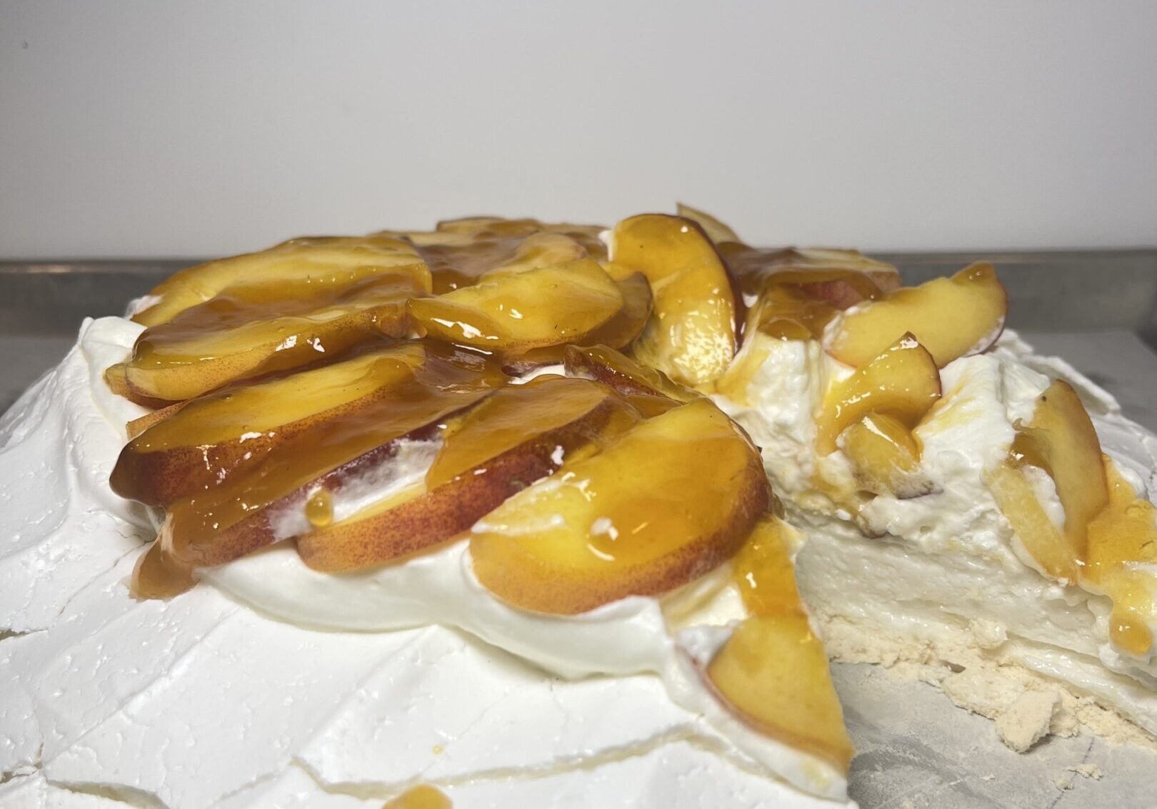 Pavlova topped with sliced peaches and cream.