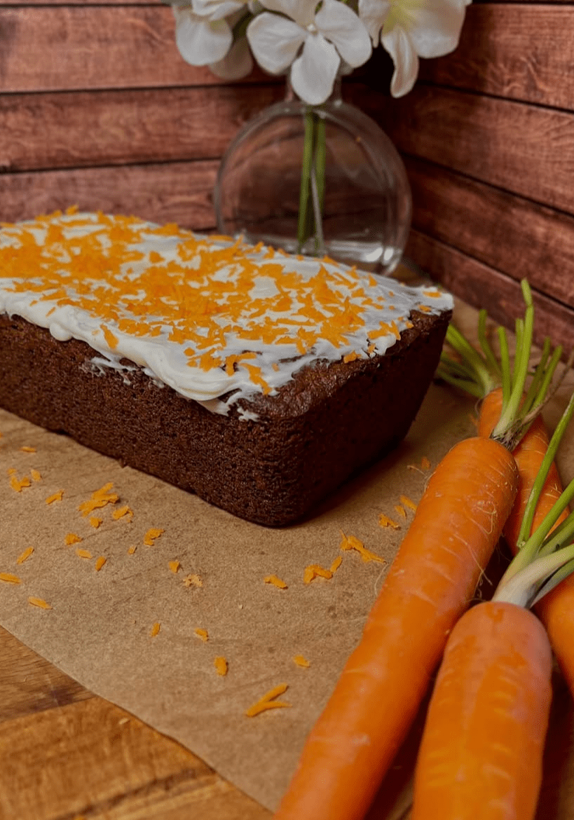 Carrot cake with frosting and fresh carrots.