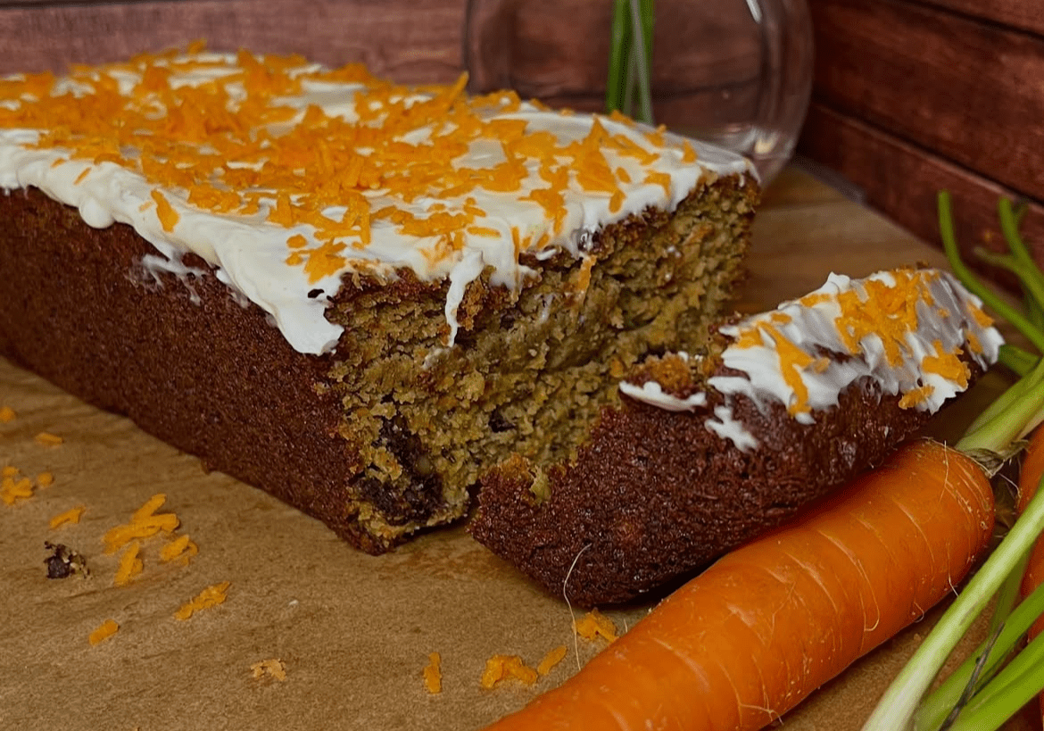 Carrot cake with frosting and fresh carrots.