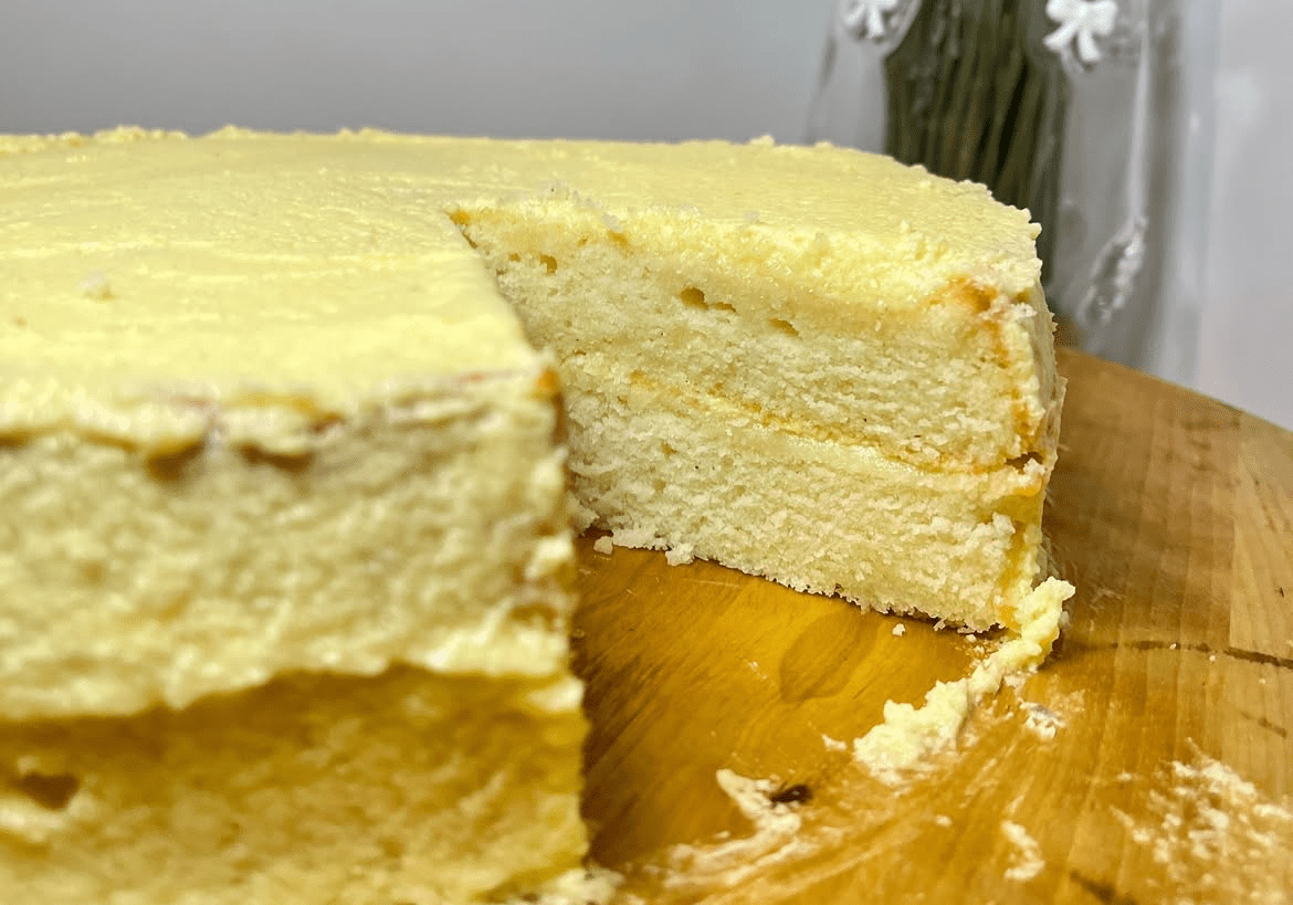 Yellow cake with slice removed on board.