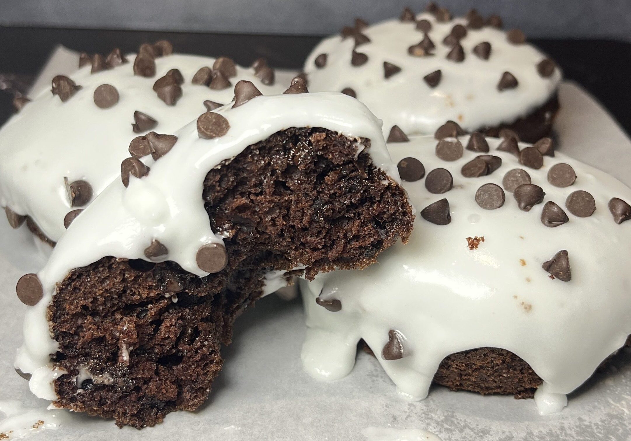 Chocolate donuts with white icing and chips.