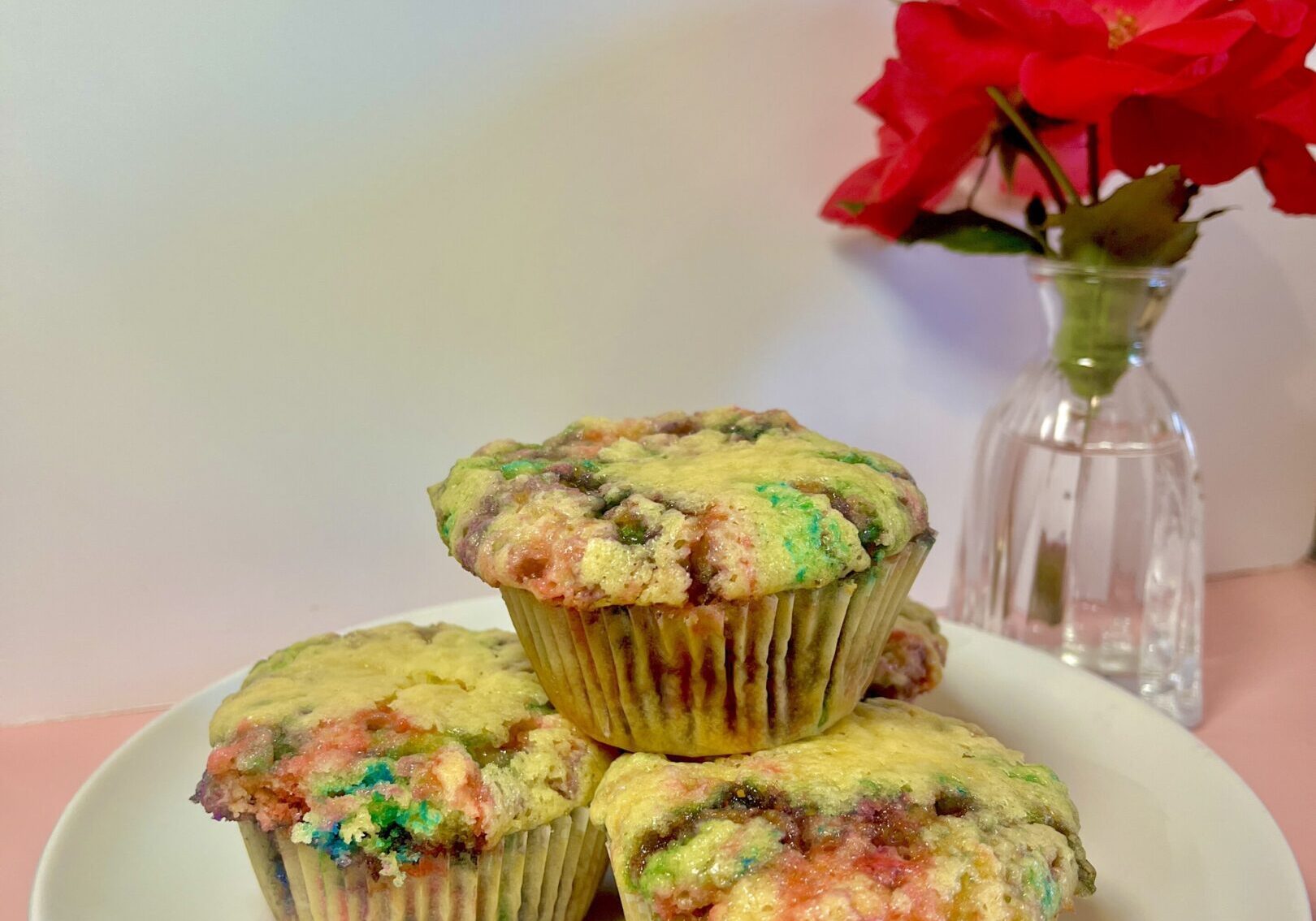 Colorful muffins on plate with red flowers.