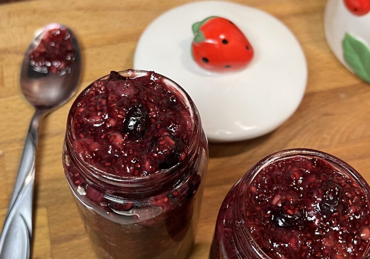 Jars of berry jam on wooden table.
