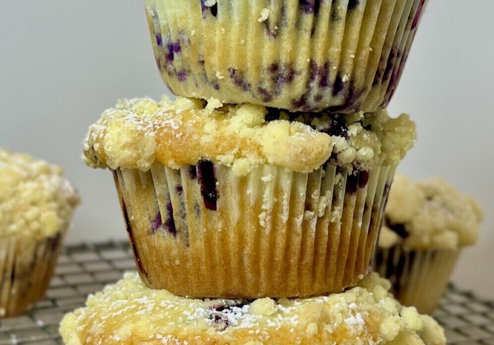 Stacked blueberry muffins with crumb topping.