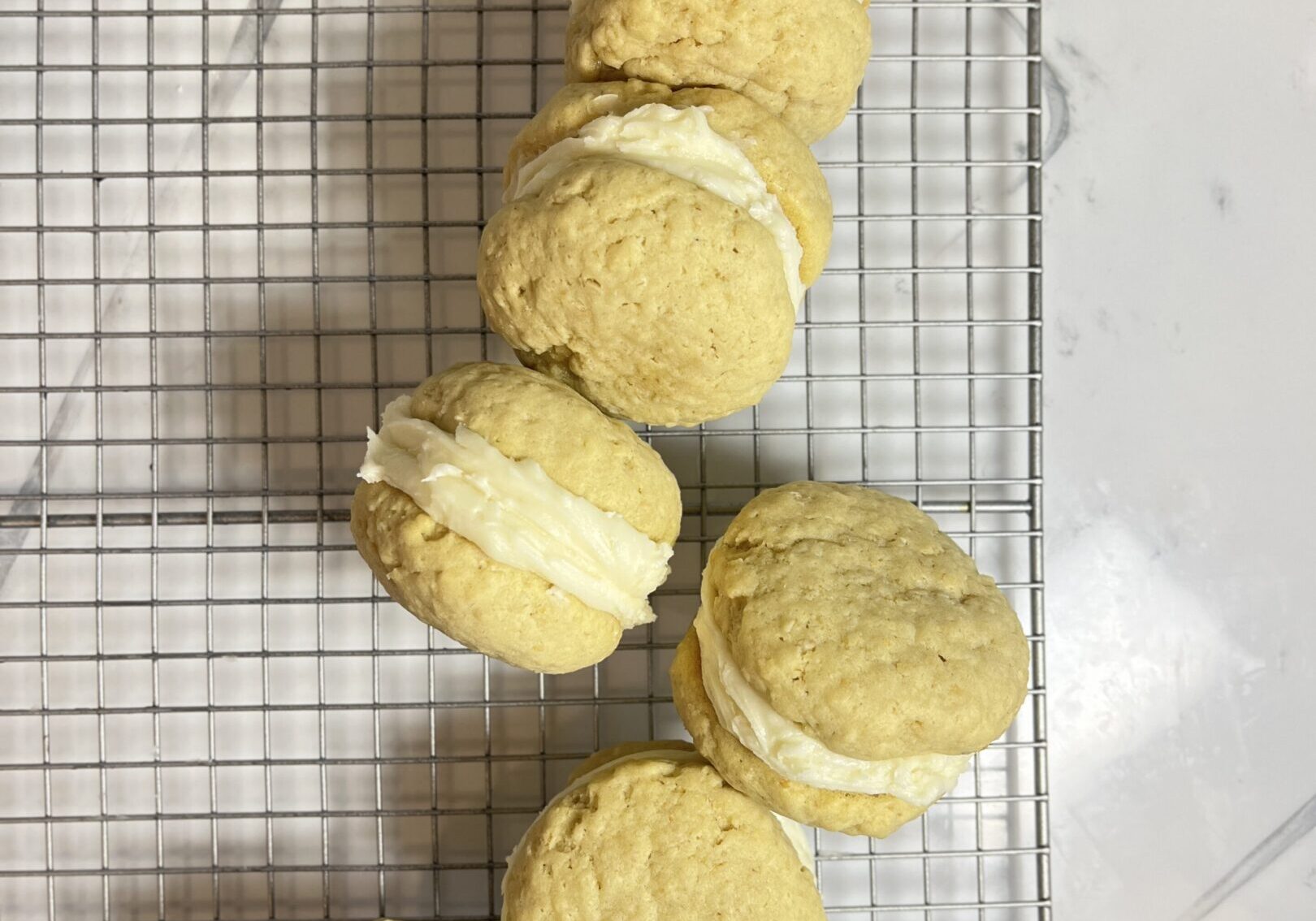 Cookies with cream filling on cooling rack.