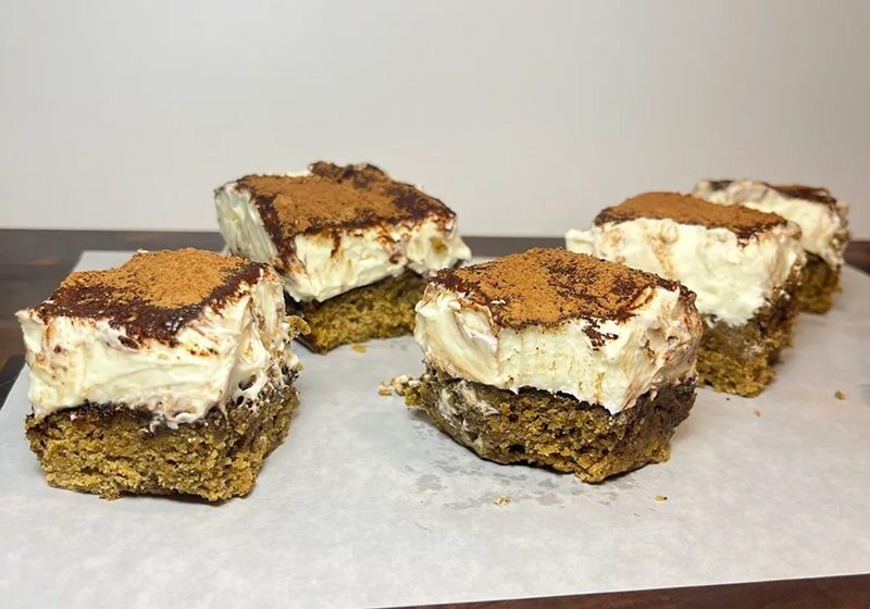 Close-up of layered dessert bars with cream and caramel topping.