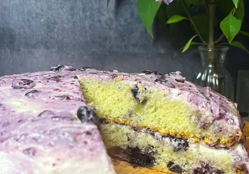 A slice of blueberry cake with creamy purple frosting.