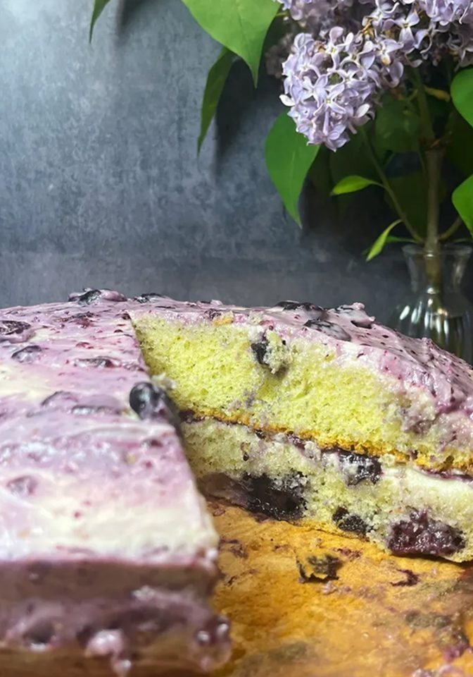 A slice of blueberry cake with creamy purple frosting.