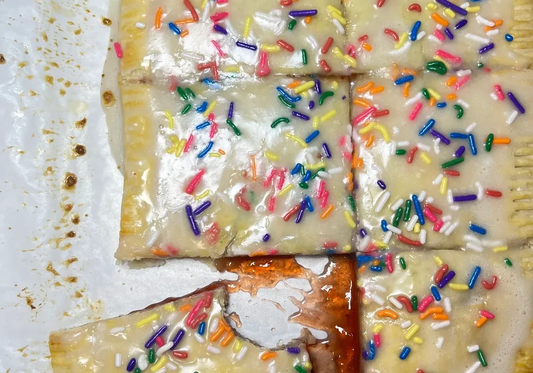 Frosted toaster pastry with colorful sprinkles, partially cut and served.